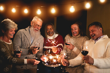 Happy multiracial people celebrating new year's eve drinking wine at home - Mature friends having...