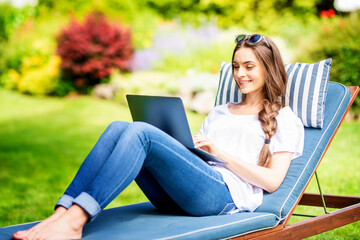 Young woman working on laptop in the garden at home