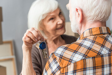 senior woman holding keys and hugging husband, moving concept