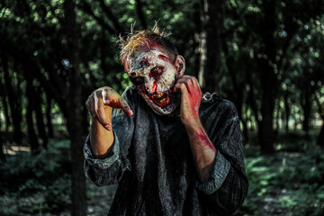 Scary zombie with bloody face outdoors. Halloween monster