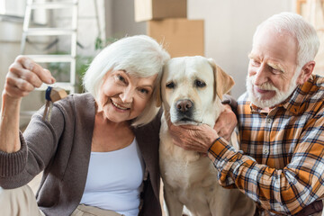 senior man petting dog while wife holding keys, moving concept