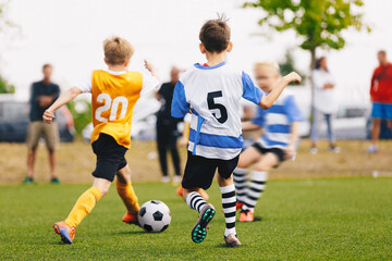 Obraz premium Children Playing Sports Soccer Match. Young Boys Compete in Football Tournament. School Boys Kicking Black and White Classic Soccer Ball