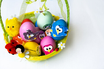 Easter eggs in pastel colors with a decor in the form of birds lie in a beautiful green basket,...