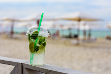 Mojito cocktail on wooden table with sandy beach on a background