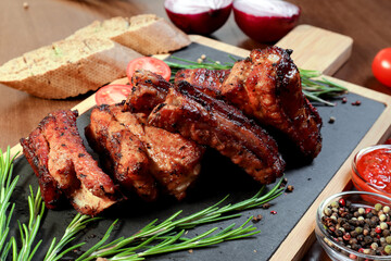Grilled pork ribs with vegetables and spices on a wooden board. European cuisine.