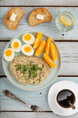 Healthy breakfast oatmeal, eggs, oranges on a blue wooden background, top view