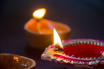 Indian festival Diwali, Diya oil lamps lit on colorful wooden background. Hindu traditional. Happy Deepavali. Copy space for text.