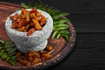 Close up of yellow raisins in a stone bowl, close up, dark background