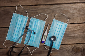 Fototapeta na wymiar .Medical masks, stethoscope and thermometer on wooden background