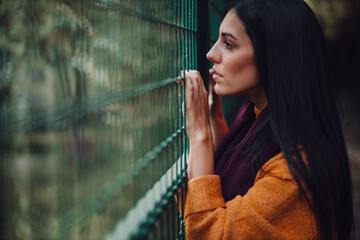 Woman looking through the metal fence in the forest