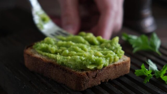 Avocado toast with fried mushrooms. Spreading mashed avocado on rye bread toast. Healthy vegan vegetarian toast
