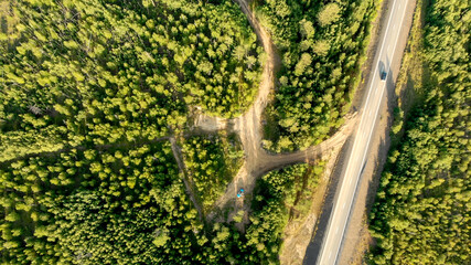Aerial view of country road with few cars driving between forests.
