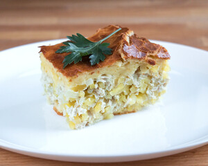 Piece of meat pie with potatoes on a white plate