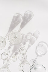 Different empty glasses on white background. Direct sunlight. Top view, flat lay, copy space.