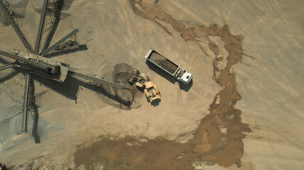 White truck with coal. Earthmoving machine for excavation and dumping. Sandy land on the background.