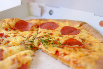 Take away Pepperoni pizza in a box delivered and started eating. High quality photo