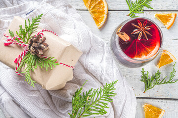 Festive Composition with Paper Craft Gift Box and Mulled Wine Glass, on wooden table with Christmas Fir Tree. Happy New Year and Christmas Greeting Card background advent