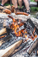 Friends roast sausages over an open fire outdoors