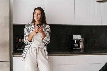 Young beautiful caucasian woman smiling and holding cellphone at home