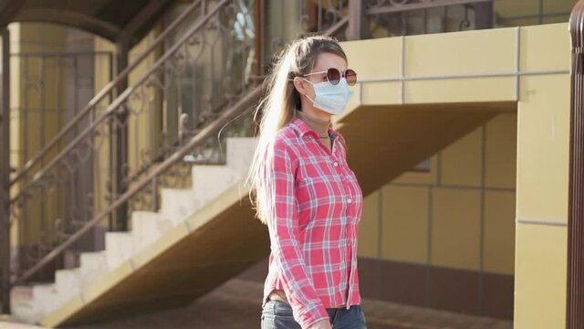Girl in a Protective Medical Mask Walking Down the Street, Close-up. Camera Slide. The Concept of Protection Against Allergies and Viruses.