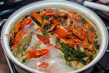 Crayfish are boiling in a large saucepan with dill on the fire