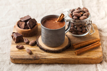 Hot chocolate in a metal mug with a cinnamon stick on the tablecloth. Copy space