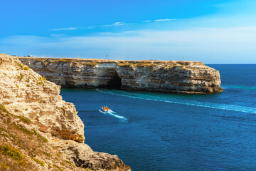 Natural caves in Crimea. Rock cliff arches on beach and turquoise sea water on coast