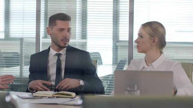 Tracking shot of unhappy businessman and businesswoman disagreeing with terms and conditions of deal and leaving conference room as middle-aged male executive gesturing and talking