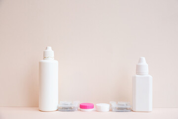 Contact lenses, lens solution and lens containers on a light pink background. Health care concept