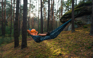 Halloween Scarecrow with a carved pumpkin in relax in Hammocks on trees in the forest it seems they...