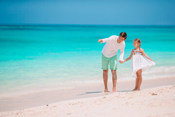 Little girl and happy dad having fun during beach vacation