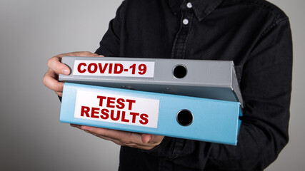 COVID-19 TEST RESULTS. Office binders in the hands of man