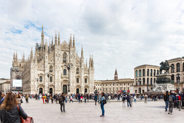 Obraz premium Numerous passers-by and tourists are walking along the Piazza del Duome square in front of the Milan Cathedral - Duomo di Milano in Milan, Italy.