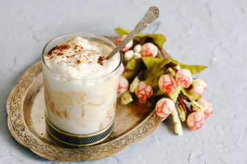 Glass of yogurt with cinnamon and caramel. Silver platter with tasty sweet dessert. Romantic morning breakfast.