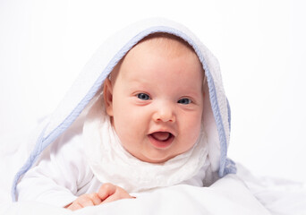 Charming and smiling baby girl lies under a towel after bathing