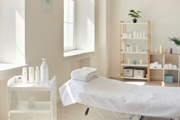 Massage room or beauty parlor with empty bed and ready set of organic skincare products