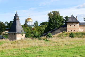 the tops of the fortress wall towers of Pskov-Pechory Dormition Monastery in Pechory, Pskov region, Russia under blue sky