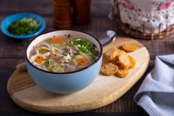 Soup with chicken, noodles, potatoes, quail eggs and carrots. Seasoned with onions and parsley. Close-up.