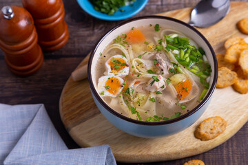 Soup with chicken, noodles, potatoes, quail eggs and carrots. Seasoned with onions and parsley. Close-up.
