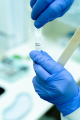 Female hands in gloves hold a test tube for taking material for coronavirus. Test tube for smear on COVID. Pandemic virus.