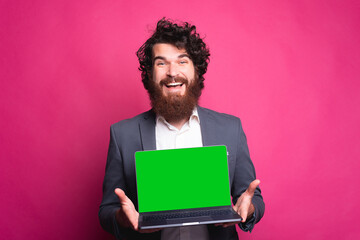 Man presenting something on laptop, cheerful bearded man in casual showing laptop with green screen