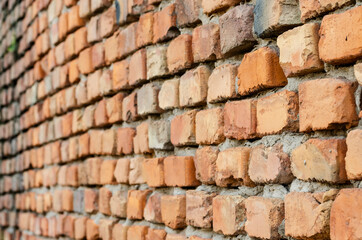 Fototapeta premium Red brick wall in receding perspective. Geometric composition of rectangular clay bricks.