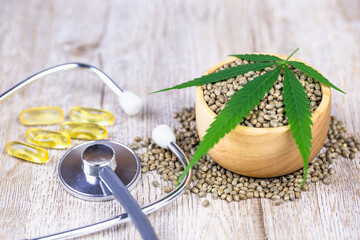 Medical stethoscope And the cannabis seeds in a wooden cup are placed on the table. The concept of treatment using cannabis as a medical extract. Alternative medicine.