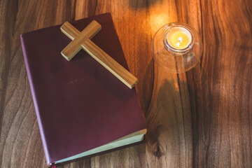 The crucifix lay on the bible. While there are candles that are illuminating Christian religious...