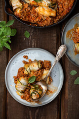 Baked zucchini rolls with ricotta cheese and herbs in meat ragu Bolognese