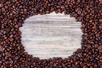 Coffee beans on wooden background. Pile of coffee. Coffee beans on a wooden background. Top view. Copy space.