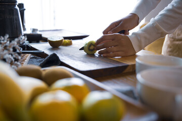 キウイフルーツを包丁で切り、調理する女性の手元