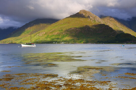 landscape image looking across Loch Duich with a sailing boat in the distance. West Highlands, Scotland, UK. 