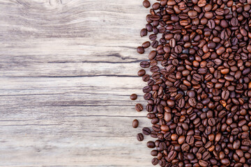 Coffee beans on wooden background. Pile of coffee. Coffee beans on a wooden background. Top view. Copy space.