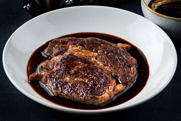 Top down view on delicious meat dinner in dark round plate with copy space over wooden table